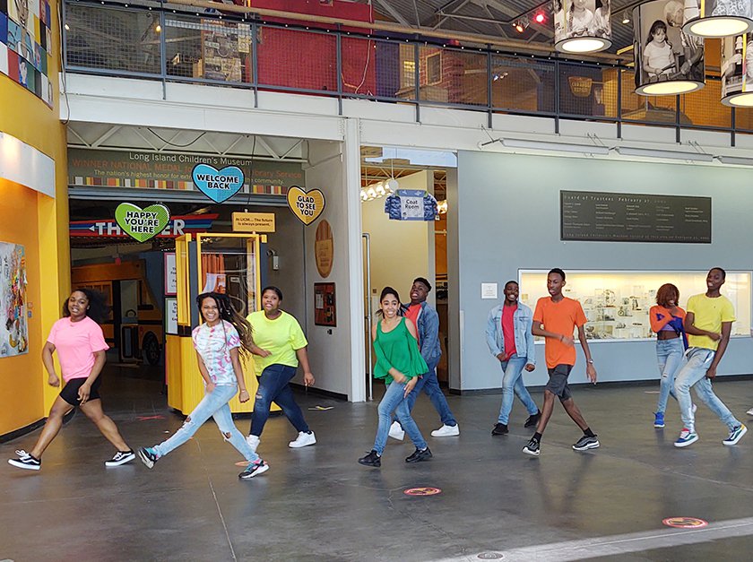 Members of the Uniondale Show Choir singing and dancing in the Museum lobby.