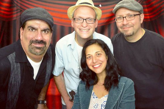Three adult men standing and one woman sitting. 