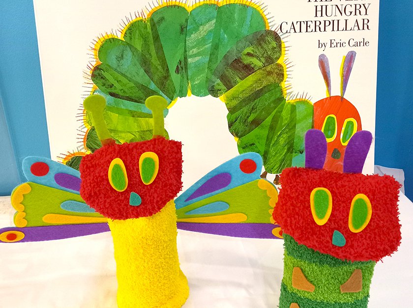 The Very Hungry Caterpillar book in the background and a fuzzy caterpillar and butterfly craft in the foreground.