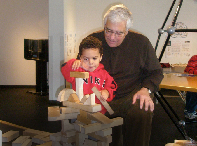 Photo of a toddler and adult building with bricks. 