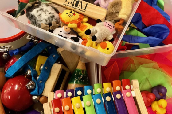 Containers filled with finger puppets, scarves, rubber ducks and musical instruments. 