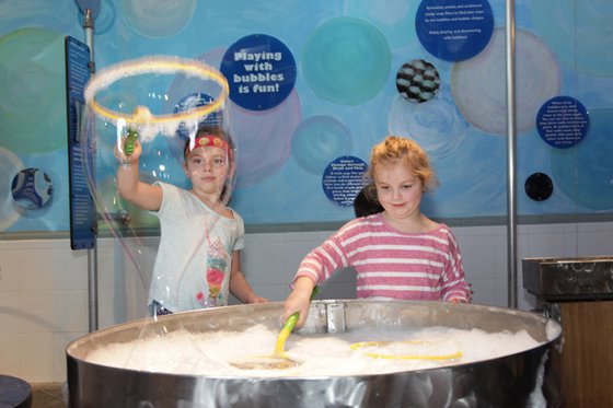 Two girls using bubbles wands to make bubbles. 