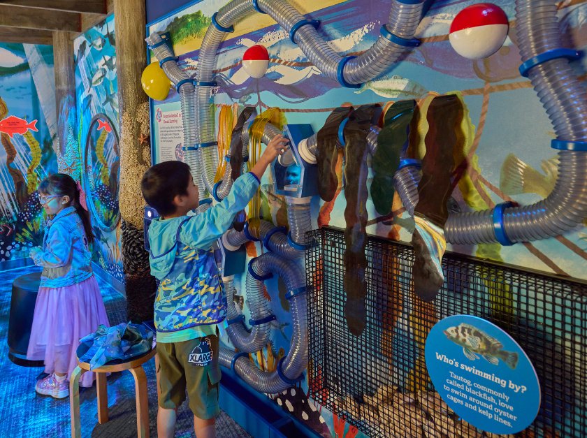 Children standing before colorful wall with underwater images and clearn air tubes.