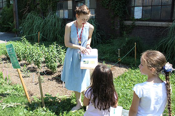 Staff member in garden of LICM with two children. 
