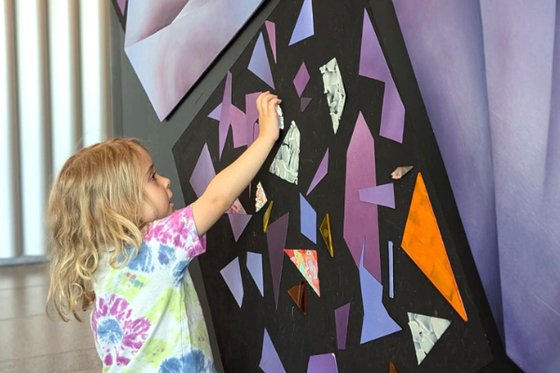 Child interacts with colored magnets on wall.