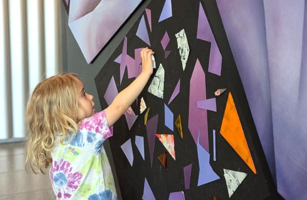 Child interacts with colored magnets on wall.