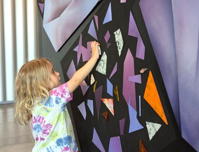 Child interacts with colored magnets on wall.