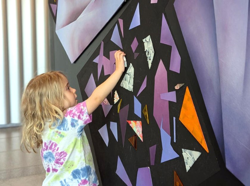 Child plays with magnets on black wall.