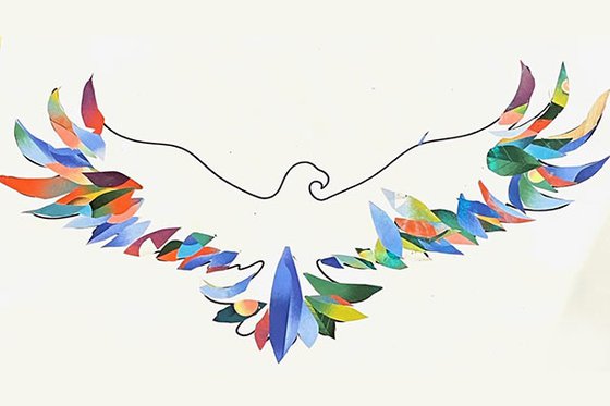 An outline of an eagle on white paper with each feather decorated with pieces of colored paper. 