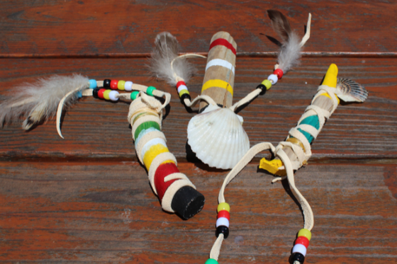 Three Indigenous talking sticks decorated with colorful beads, feathers and shells.