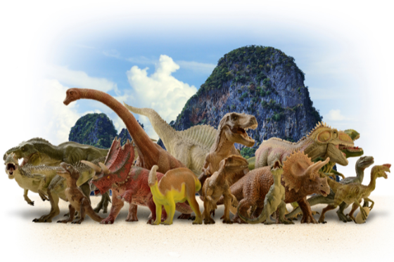 An animated image of a large and variety group of dinosaurs with a large rock and sky in the background. 