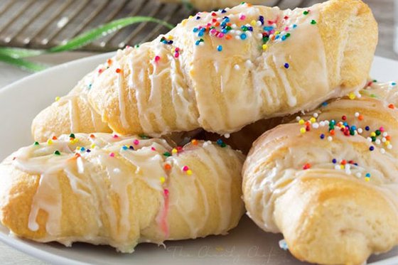 Croissants topped with frosting and sprinkles. 
