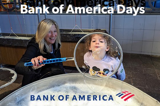 Woman holding bubble wand as young girl blows giant bubble.