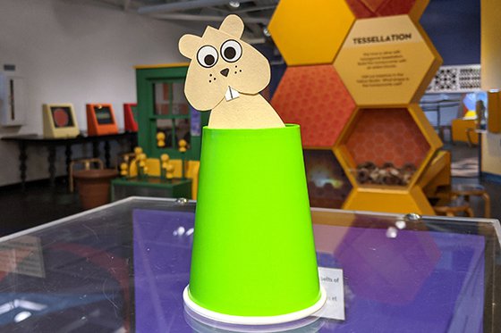 A paper groundhog emerging from a green paper cup. 