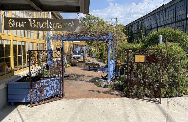 The entrance to 'Our Back Yard,' the LICM's garden.There is a sign with the name and a blue gate.