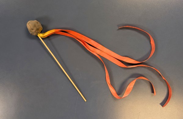 A clay meteor attached to a dowel with 'fire' streamers. 