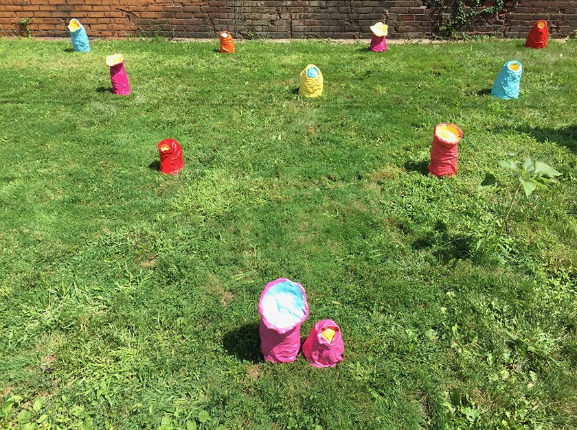 Multiple colorful sculptures representing swaddled babies on the lawn of LICM. 