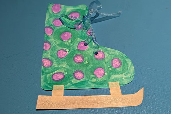 A paper green and purple ice skate with ribbon laces. 