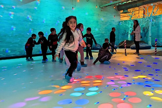 A group of children gliding on the plastic "ice" surrounded by colorful lights. 