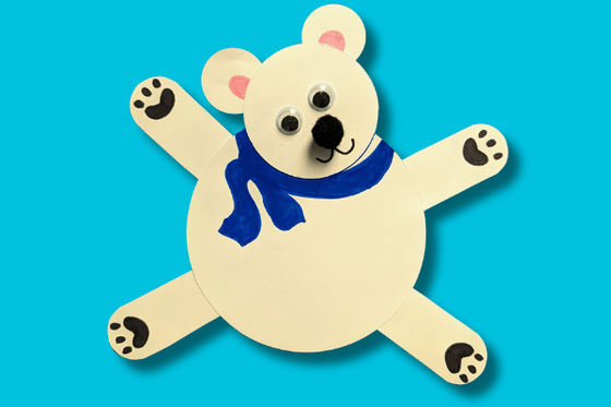 A white paper polar bear with large eyes and a blue scarf. 