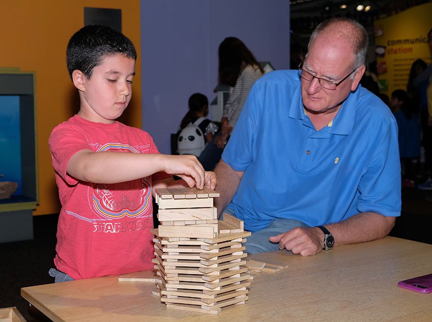 Child and adult building a KEVA structure together