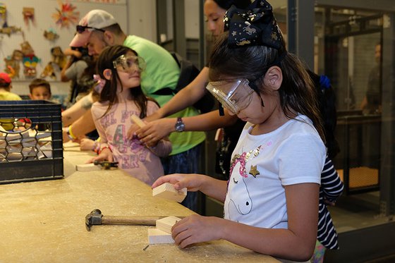 Young visitor wearing goggles building with a hammer in Tool Box