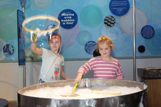 Two girls using bubble wands to make bubbles.