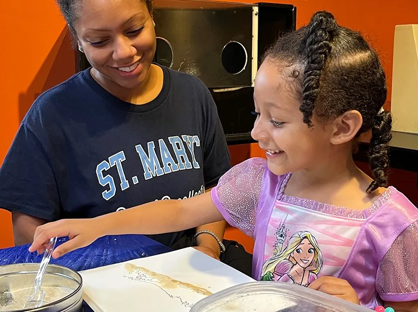 A child and adult making a textured map of Long Island.