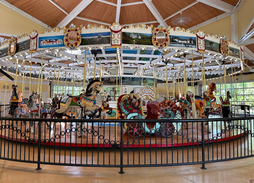 A historical hand-carved carousel behind a black fence.