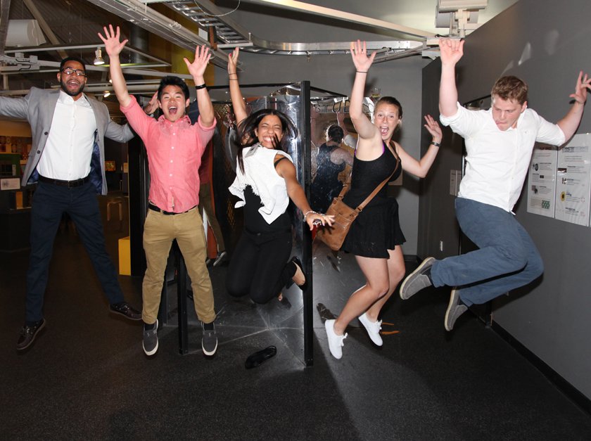 Adults jumping up with their hands in the air at the Museum.