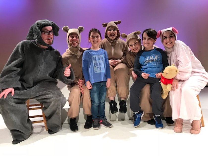 Five actors in costume pose with two members of the audience on LICM stage.