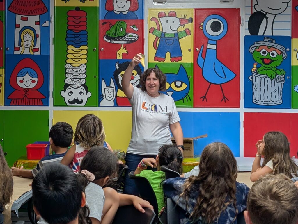 Museum educator in white LICM shirt holds fossil up to class