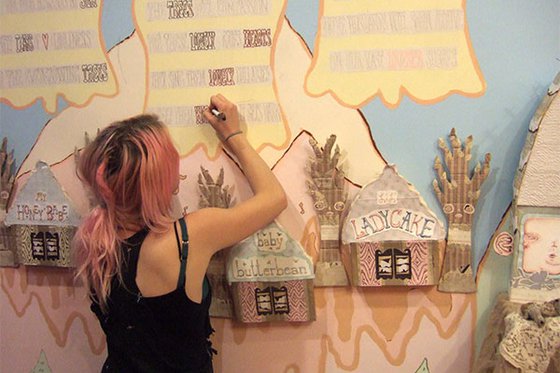 An artist creating a mural which includes store fronts using a marker.
