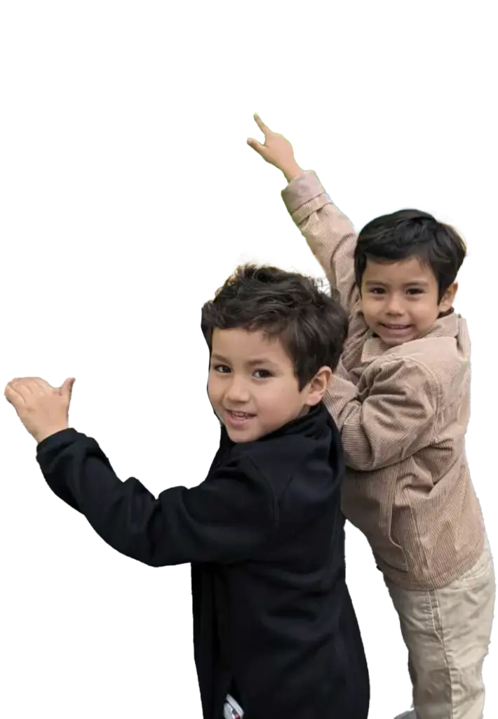 Two boys smiling, one pointing upward, shown on a plain background.